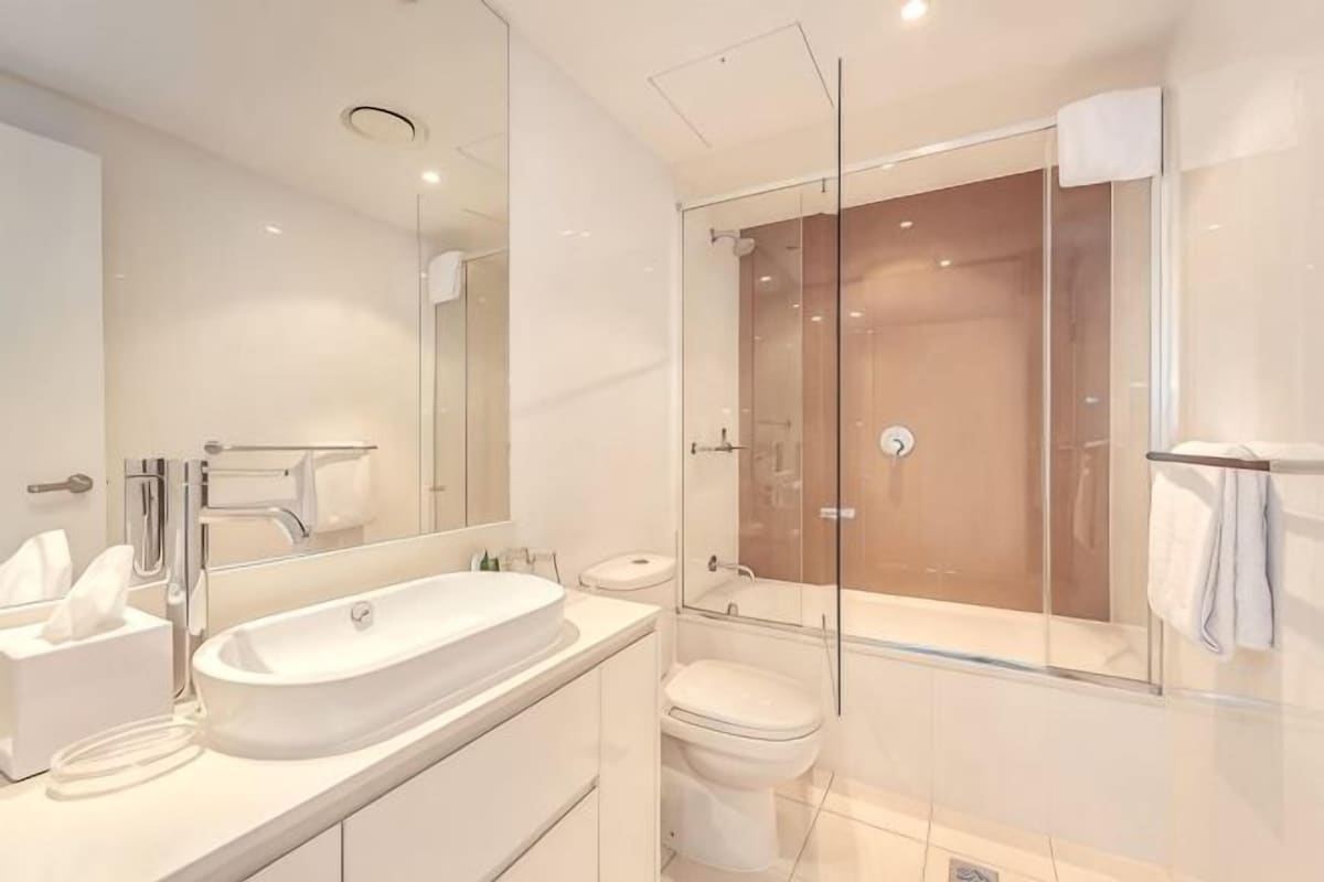 A modern bathroom with a glass-enclosed shower, a large sink, and a toilet.