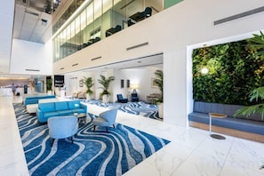 A spacious lobby with a high ceiling, seating areas, a patterned carpet, and a vertical garden wall.