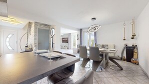 A modern dining area with a dark wooden table, grey chairs, and a large mirror.