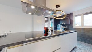 A modern kitchen with a large island, stainless steel appliances, and a unique circular light fixture.