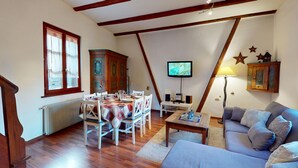 A dining area with a table set for four, a television mounted on the wall, and a sofa in the living room. - Zum Bären Duplex - 1 Parking (Colmar)