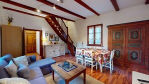 A cozy living room with a sofa, a wooden coffee table, a staircase, a dining area with a table and chairs, and a cabinet. - Zum Bären Duplex - 1 Parking (Colmar)