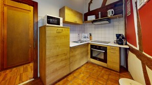 A compact kitchen with wooden cabinets, a microwave, a sink, and a stove. - Zum Bären Duplex - 1 Parking (Colmar)