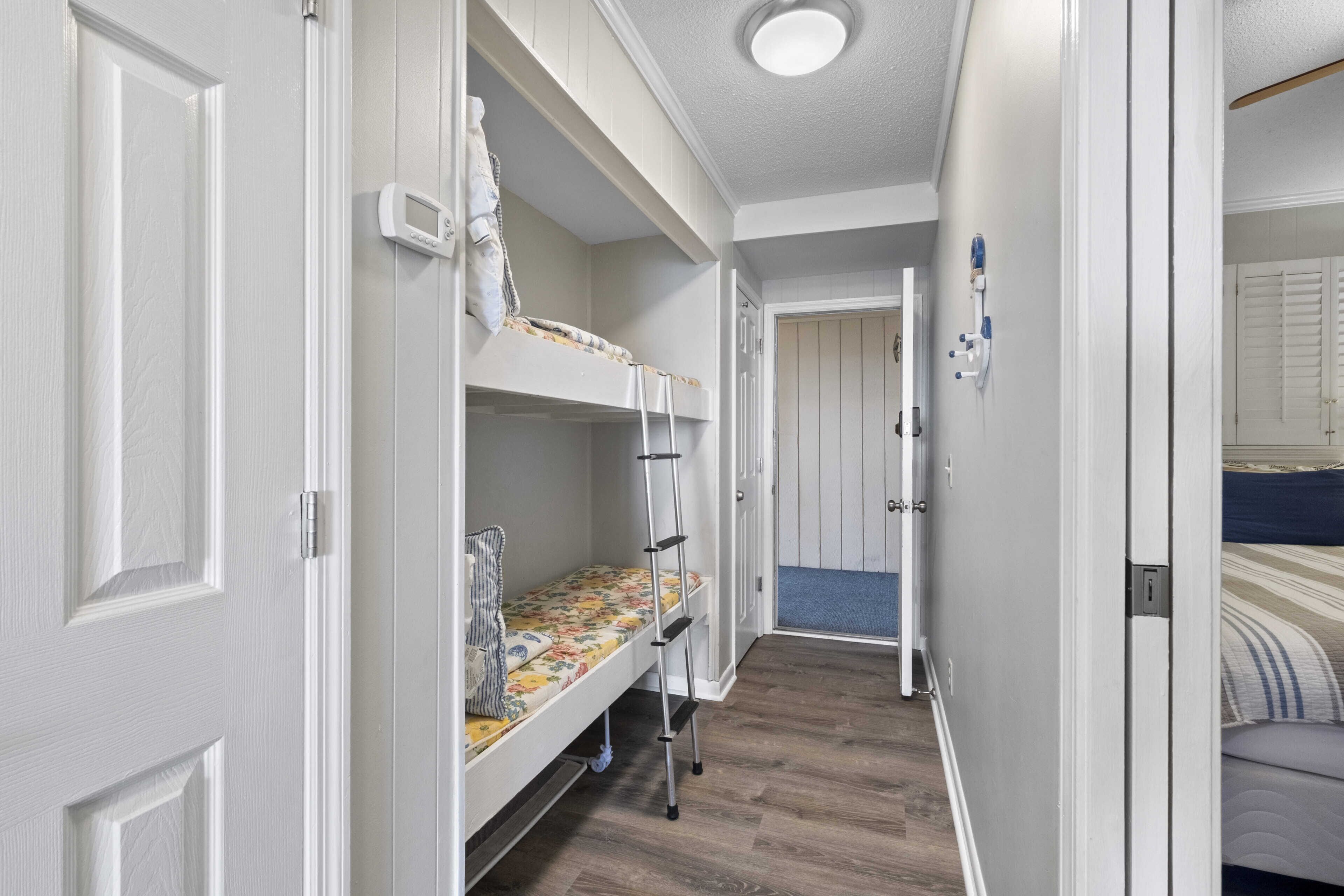A narrow hallway with bunk beds and a door leading to another room.