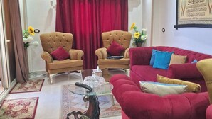 A living room with a red sofa, two armchairs, a glass coffee table, and a decorative horse statue.