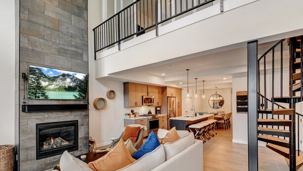 A spacious living area with a fireplace, a sofa with cushions, a dining area, and a kitchen.