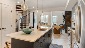 A modern kitchen with a central island, stainless steel appliances, and pendant lighting.