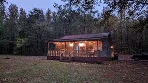 Une cabane dotée d’une véranda, d’un escalier et offrant une vue sur la forêt environnante.