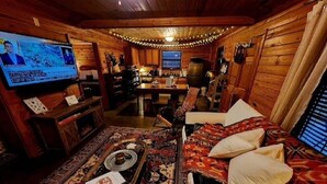 Un intérieur chaleureux de chalet en bois, avec un téléviseur, des meubles en bois et un coin repas.