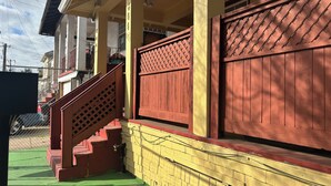 Un edificio con fachada amarilla, escalones de madera rojos y un portón rojo.
