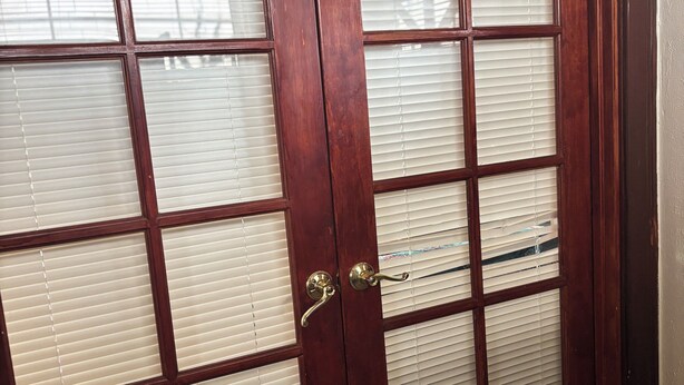 Una puerta de madera con varios paneles de vidrio y un tirador de latón.