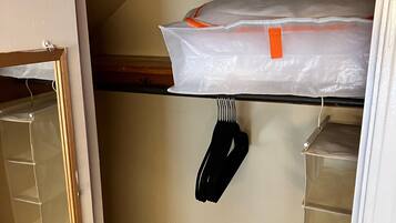 Un armario para guardado con estantes, una percha y una bolsa de plástico en el estante superior.