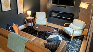 A modern living room with a sofa, two armchairs, a coffee table, a TV, and a fireplace. - Stunning 2-bedroom Home w/ WiFi, AC in Brookline Pittsburgh,PA (Pittsburgh)