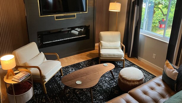 A modern living room with a flat-screen TV mounted on the wall, a sofa, a chair, a coffee table, and a lamp. - Stunning 2-bedroom Home w/ WiFi, AC in Brookline Pittsburgh,PA (Pittsburgh)