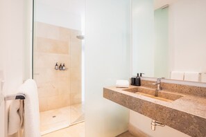 A modern bathroom with a glass-enclosed shower, a granite countertop sink, and a large mirror. - Casa Catalina de Mokana By SoHo (Cartagena)