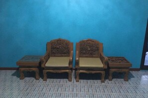 Una stanza con una parete blu e un pavimento piastrellato. Sono presenti due sedie in legno con sedili e schienali imbottiti.