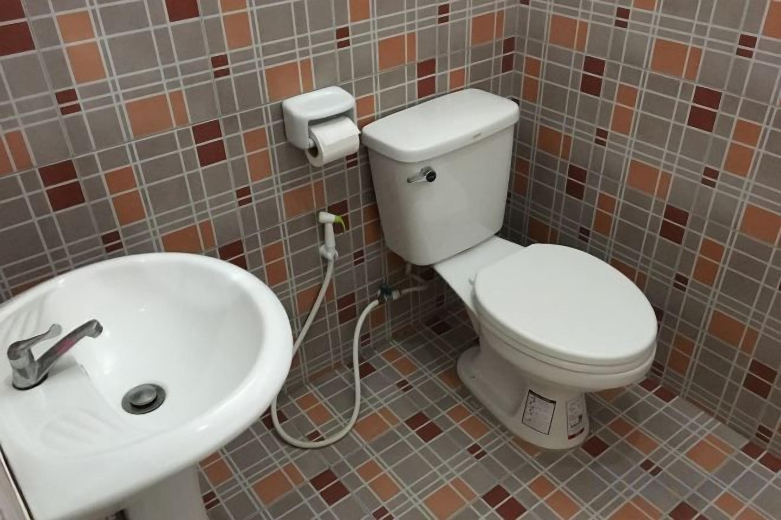 A bathroom with a toilet, sink, and tiled walls.