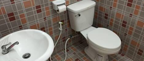 A bathroom with a toilet, sink, and tiled walls.