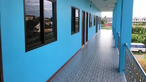 A long corridor with blue walls and tiled flooring, leading to a balcony with a metal railing. - Ban Kai Na (Hua Hin)
