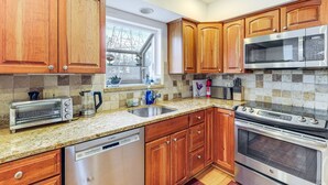 Una cocina con armarios de madera, un microondas de acero inoxidable, un tostador y un lavavajillas.