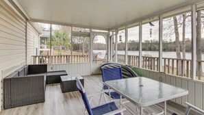 A covered outdoor seating area with wicker furniture and a glass table, overlooking a body of water and trees. - Saluda River Retreat w/ Boat Ramp & Water Views! (Prosperity)