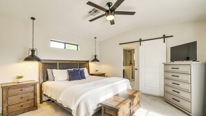 Ein Schlafzimmer mit einem Bett, Nachttischen, einer Kommode, einem Deckenventilator und einem Fernseher.