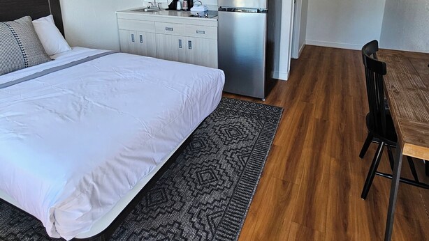 A compact hotel room with a bed, a kitchenette, a dining area, and a bathroom. - Varsity West (Centralia)