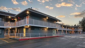 A multi-story motel with a balcony on the second floor, a parking lot in front, and a clear sky. - Varsity West (Centralia)