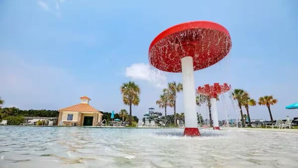 A water feature with a large red structure in the center, surrounded by palm trees and a small building with a tiled roof. - Getaway home, Savannah spot (Port Wentworth)