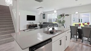 A modern kitchen with a dishwasher, a dining area with a table and chairs, and a staircase. - Getaway home, Savannah spot (Port Wentworth)