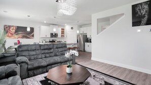 A modern living room with a grey sofa, a coffee table with a plant, and a large painting on the wall. - Getaway home, Savannah spot (Port Wentworth)