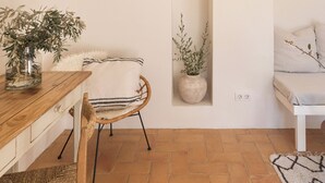 A cozy room with a wooden dining table, a wicker chair, a white sofa, and two hanging wicker lamps. - Can Palou Fornalutx (Fornalutx)