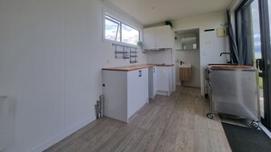 A modern kitchen with white cabinets, a wooden countertop, and a stainless steel refrigerator. - Marvelous cabin with AC in Helena Bay (Helena Bay)