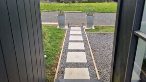 A pathway leading to a scenic view of a green field and hills. - Marvelous cabin with AC in Helena Bay (Helena Bay)