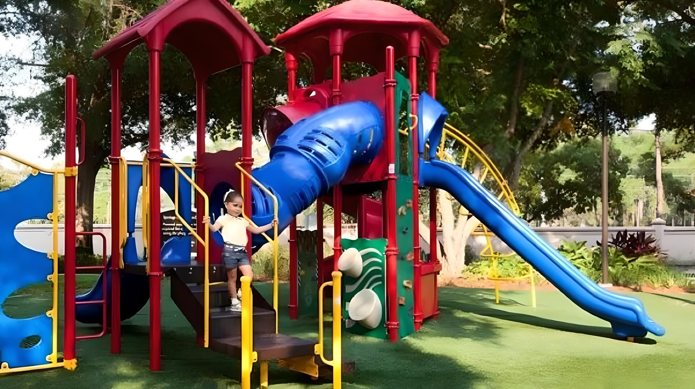 Un'area giochi con uno scivolo blu e strutture rosse.