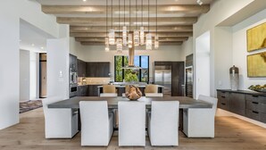 Una cocina moderna con una isla central, iluminación colgante y vistas al exterior.