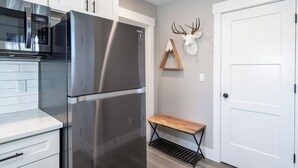 A kitchen with stainless steel appliances, a wooden bench, and a mounted deer head.