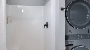 Un baño moderno con una bañera blanca, un inodoro y una lavadora.