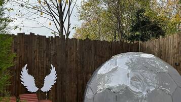 A transparent dome structure on a wooden deck with a wooden fence in the background.