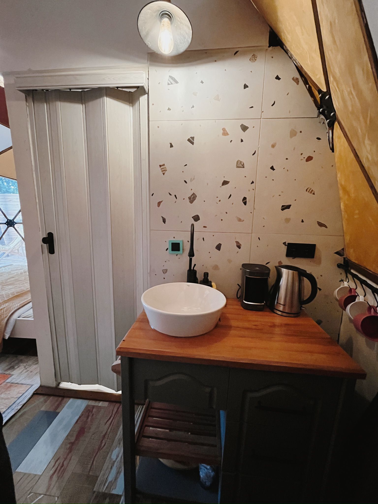 A compact kitchen with a white sink, wooden countertop, and a coffee maker.