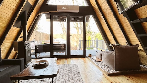 A cozy attic room with a sloped ceiling, a fireplace, a dining table, and a large window offering a view of the outdoors. - RC Sapanca (Sapanca)