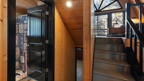 A wooden interior with a black door, a staircase, and a skylight. - Sweetin Summit Retreat (Duck Creek Village)