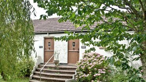 A quaint building with two wooden doors, a stone staircase leading to the entrance, and a wooden bench in the foreground. - 2 bedroom accommodation in Looe (Looe)