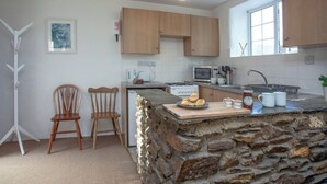 A kitchen with wooden cabinets, a stone island, a microwave, and a kettle. - 2 bedroom accommodation in Looe (Looe)