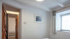A bedroom with a bed, two towels, a framed picture, and a window with curtains. - 2 bedroom accommodation in Looe (Looe)