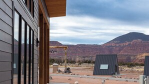 Un edificio moderno con ventanas amplias y un paseo techado que conduce a un paisaje montañoso.