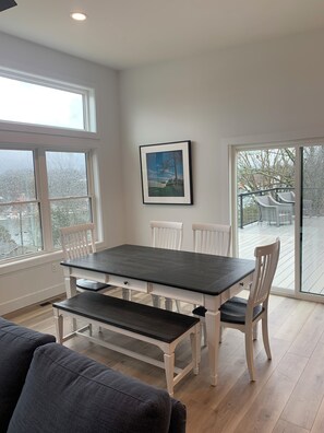 A dining area with a dark wooden table and white chairs, large windows, and a view of the outdoors. - BRAND NEW 4 bedroom 3.5 bath retreat in Williamstown, KY with large rooftop deck (Williamstown)