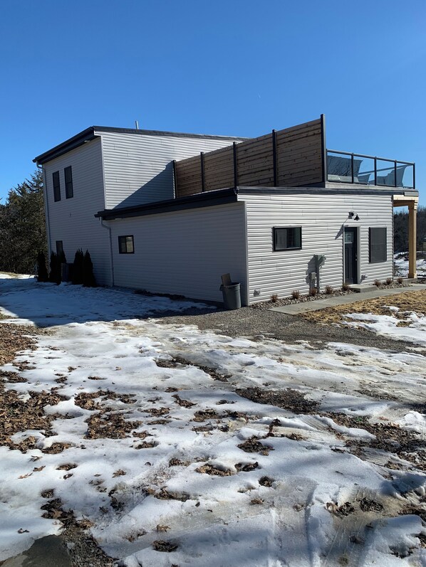 A modern two-story house with a large glass balcony on the upper floor.