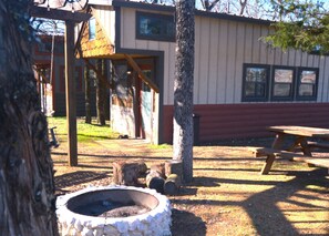 A rustic outdoor area with a wooden swing set, a picnic table, and a fire pit. - Tiny Home Resorts (Denison)
