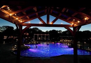 A gazebo with a pool illuminated by blue lights, surrounded by trees and buildings. - Tiny Home Resorts (Denison)